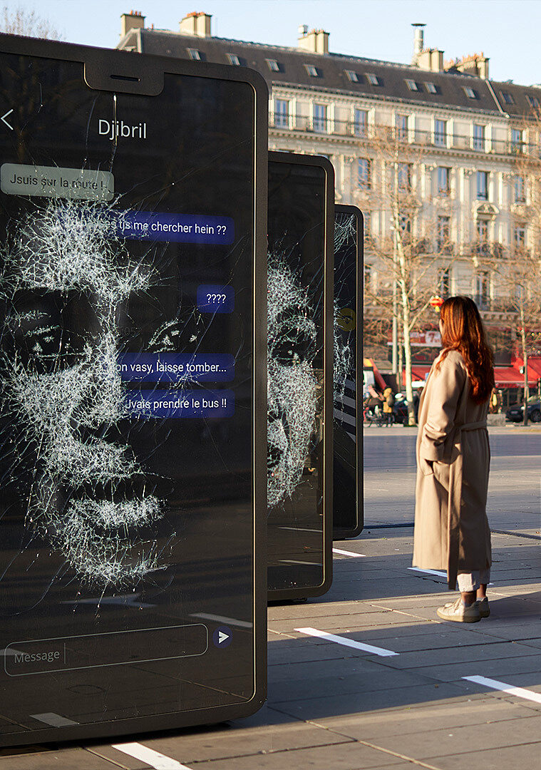 A woman observes the “Vies Brisées” exhibition on Place de la République in Paris.