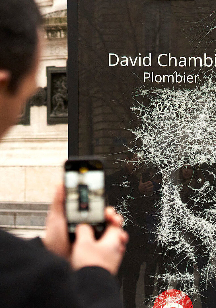 A passerby takes a photo of a shattered portrait from the exhibition.