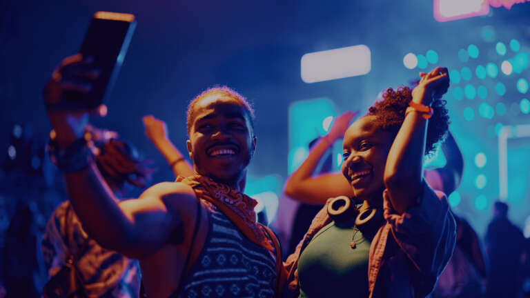 Two smiling friends taking a selfie in the evening, embodying conviviality and the pleasure of being together