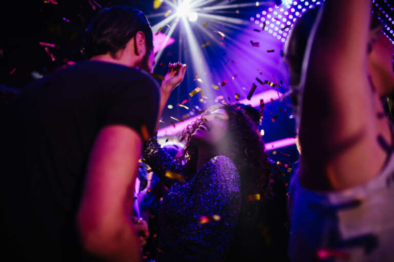 People dancing at a party while confetti is spreading around.